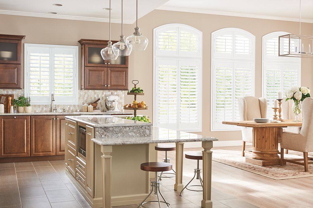 Modern kitchen featuring custom interior shutters, wooden cabinetry, and a spacious island with granite countertop, enhancing the elegant atmosphere of the dining area.